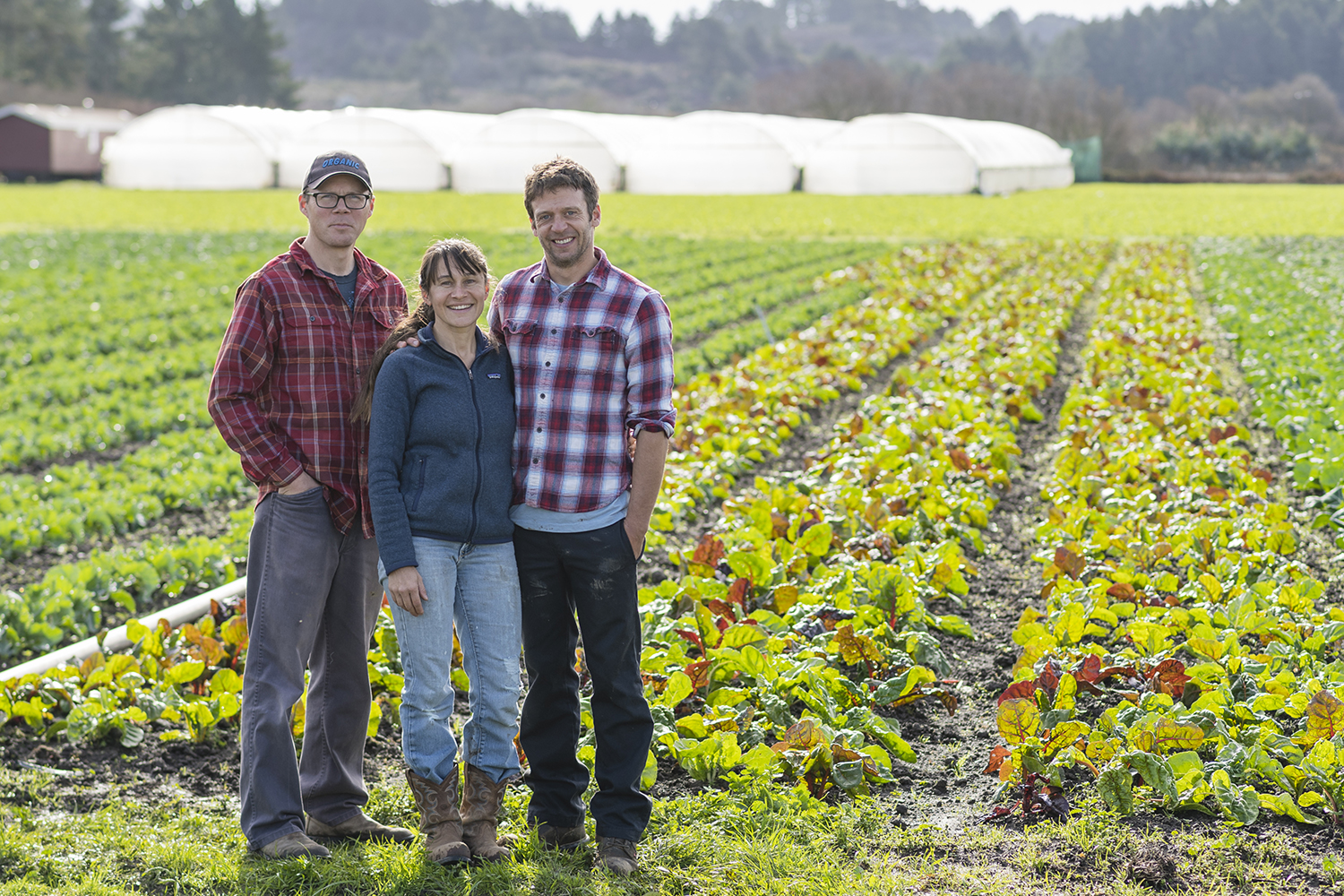 Teresa Kurtak, John Vars, and Mike Irving of Fifth Crow Farm standing in their organic apple orchard in Pescadero California